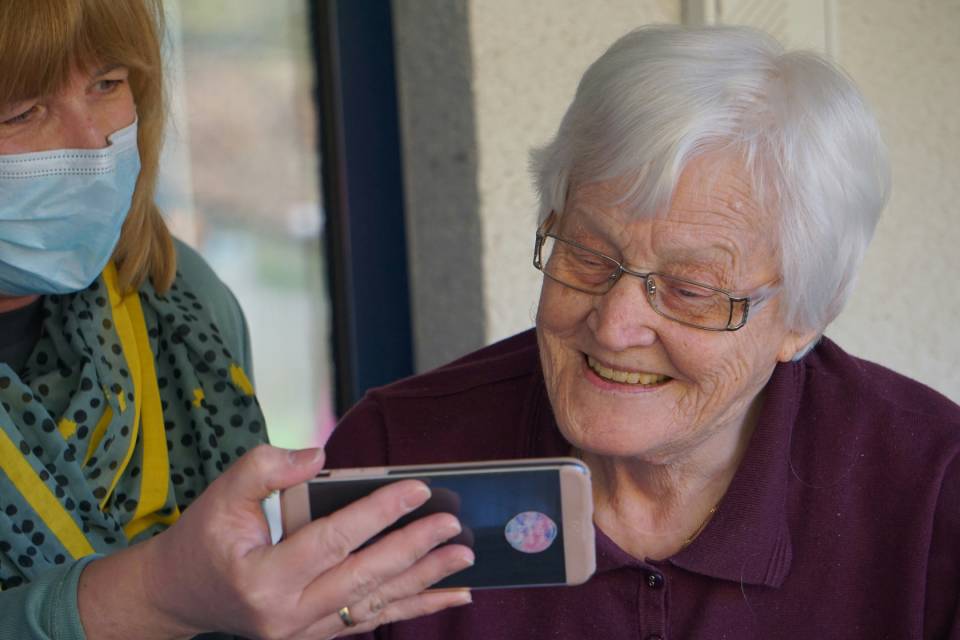 Lächelnde ältere Frau mit Handy bei einer Individuellen Betreuung